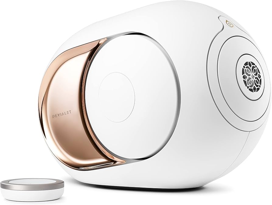 Devialet Phantom I 108 dB wireless speaker in white with rose gold side panel, next to its remote control.