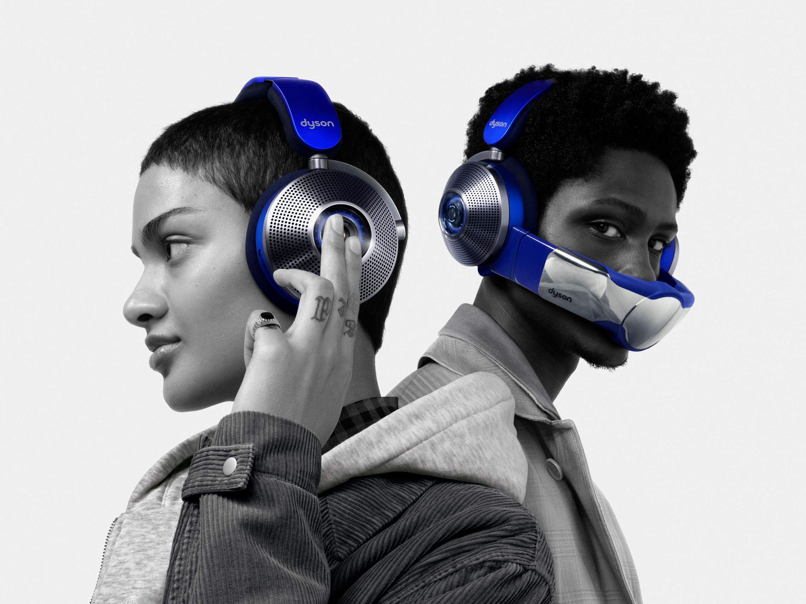 Two models wearing Dyson Zone blue & silver noise-cancelling headphones with attached air purification visors.