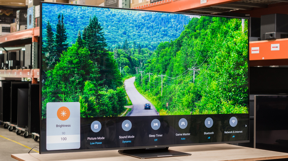 TCL QM8 Mini-LED TV showing a lush green forest scene and an on-screen menu with brightness and settings.