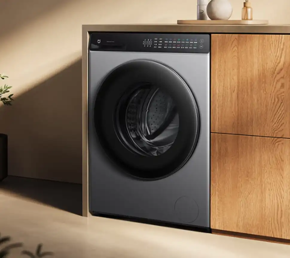 Sleek grey Xiaomi Mijia smart front-load washing machine with a black control panel, integrated into modern wooden cabinets.