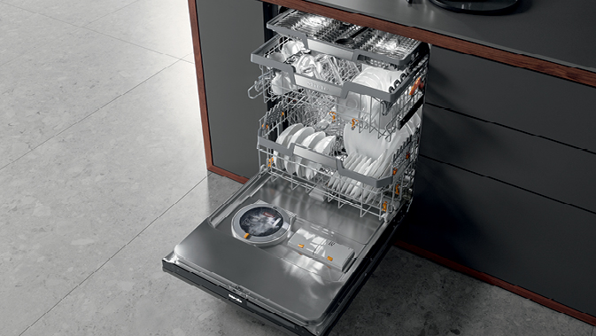 Miele G 7000 smart dishwasher open and fully loaded with clean dishes in a sleek modern kitchen.