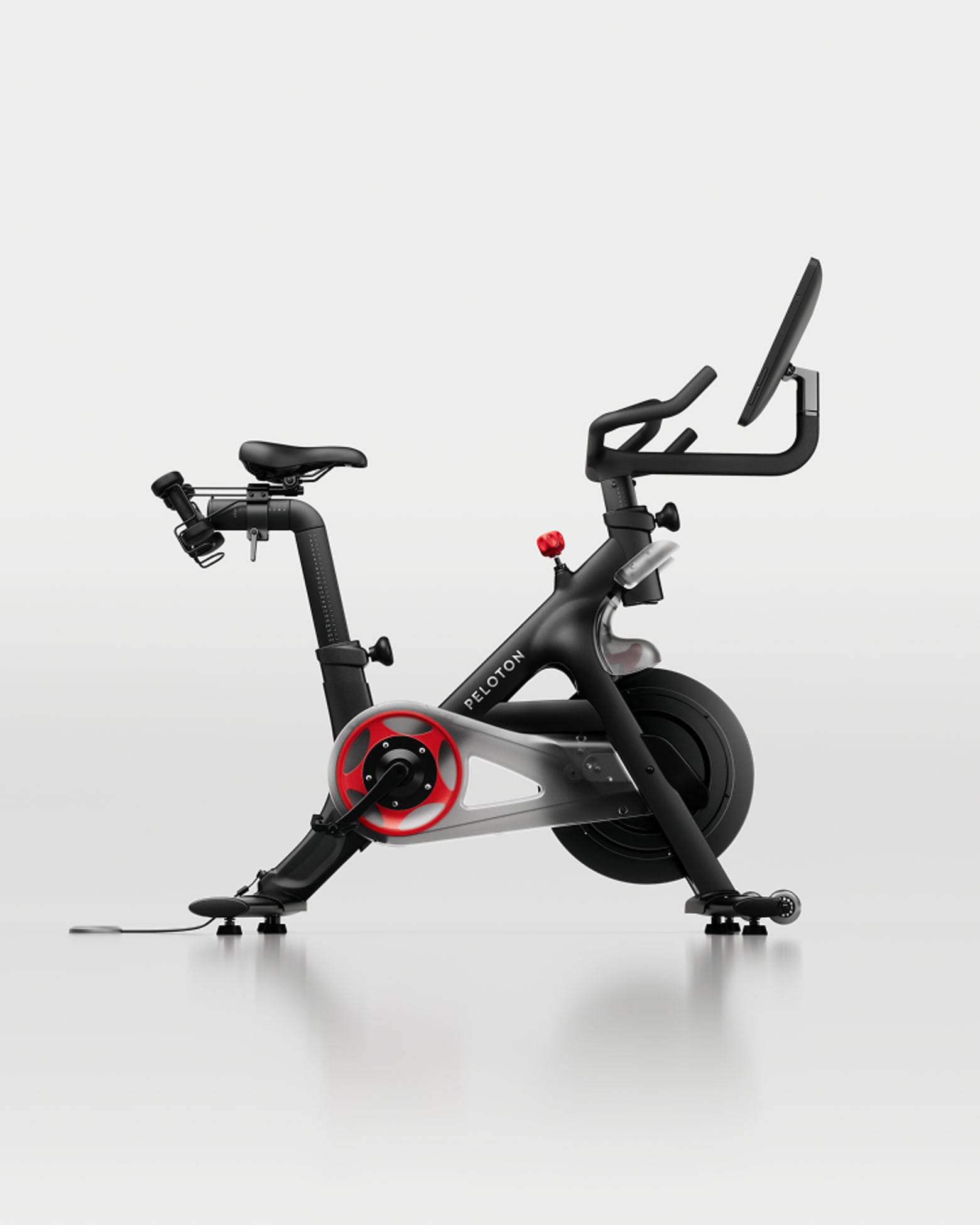 Full view of a black Peloton Bike+ stationary bike with a large screen and red accents on a white background.