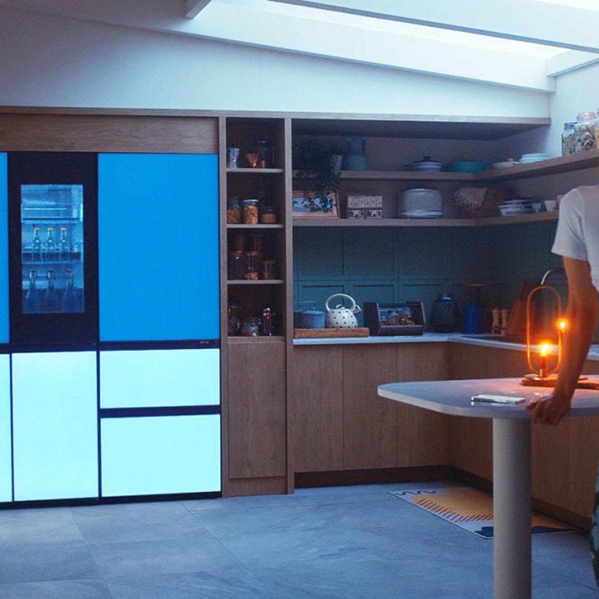 Modern kitchen featuring an LG MoodUP refrigerator with glowing blue and light blue customizable panels.