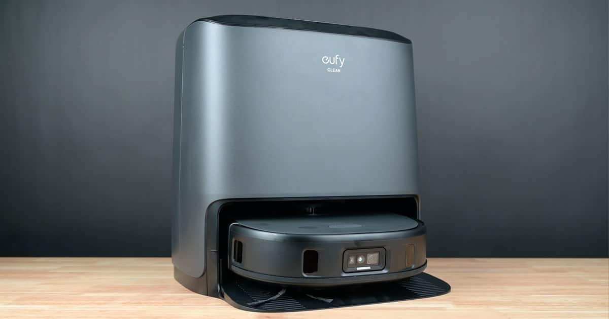 Eufy Clean X9 Pro robot vacuum and mop docked in its grey auto-empty station on a wooden floor.
