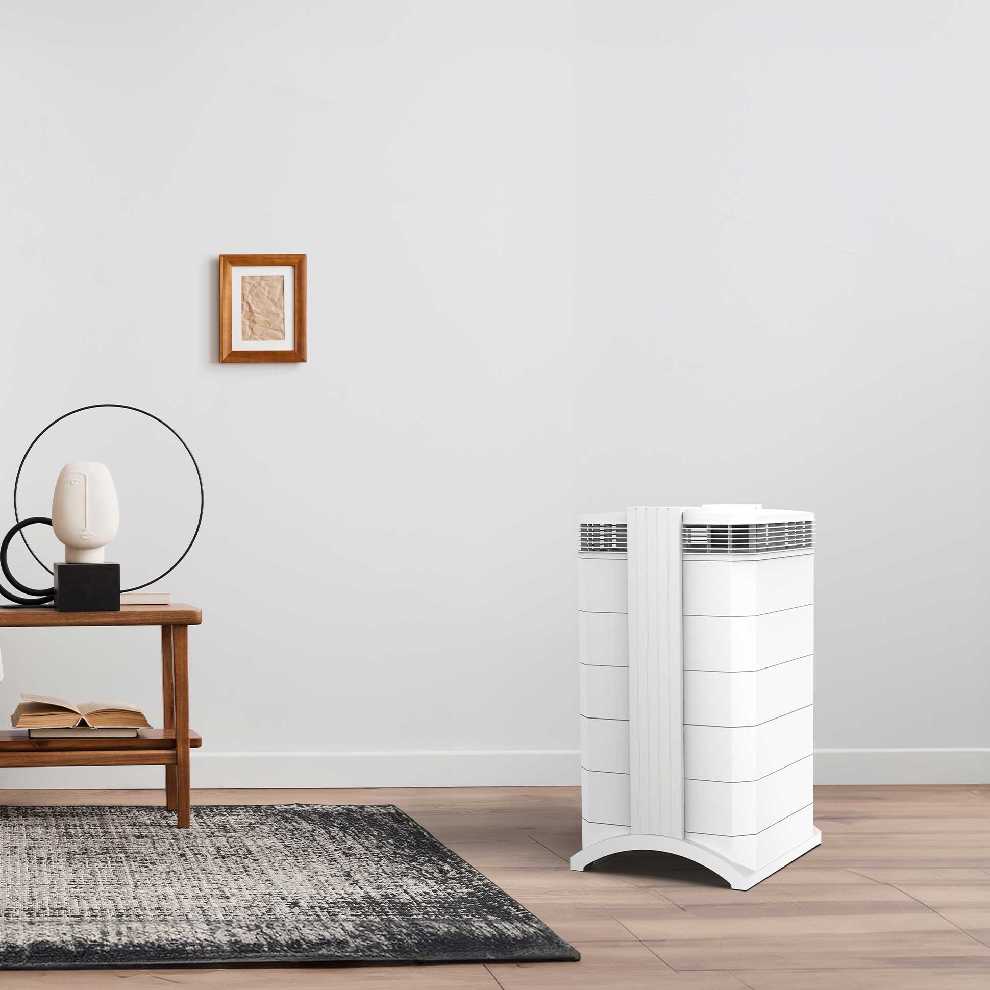 White IQAir HealthPro Plus air purifier in a clean, modern room with wooden floors and a minimalist side table.